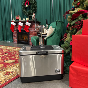 Silver cooler with black base in a festive room with Christmas tree and presents.