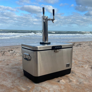 Stainless steel beer cooler with tap on a sandy beach